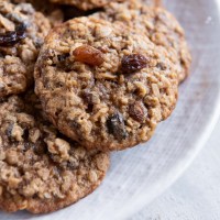 Close up of oatmeal raisin cookies stacked on a plate.