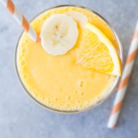 Orange smoothie in a glass with a straw.