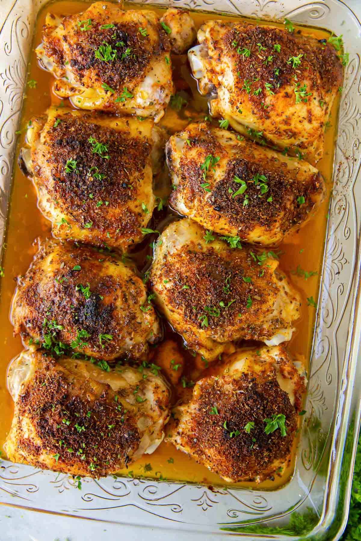 Eight baked bone in chicken thighs in a baking dish.