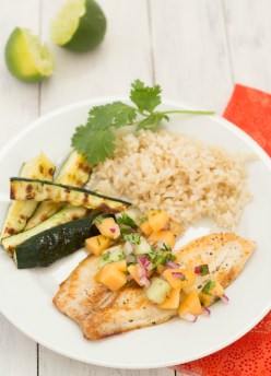 pan seared tilapia on plate with sides of rice and zucchini