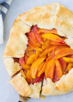 Whole peach galette with a slice cut.