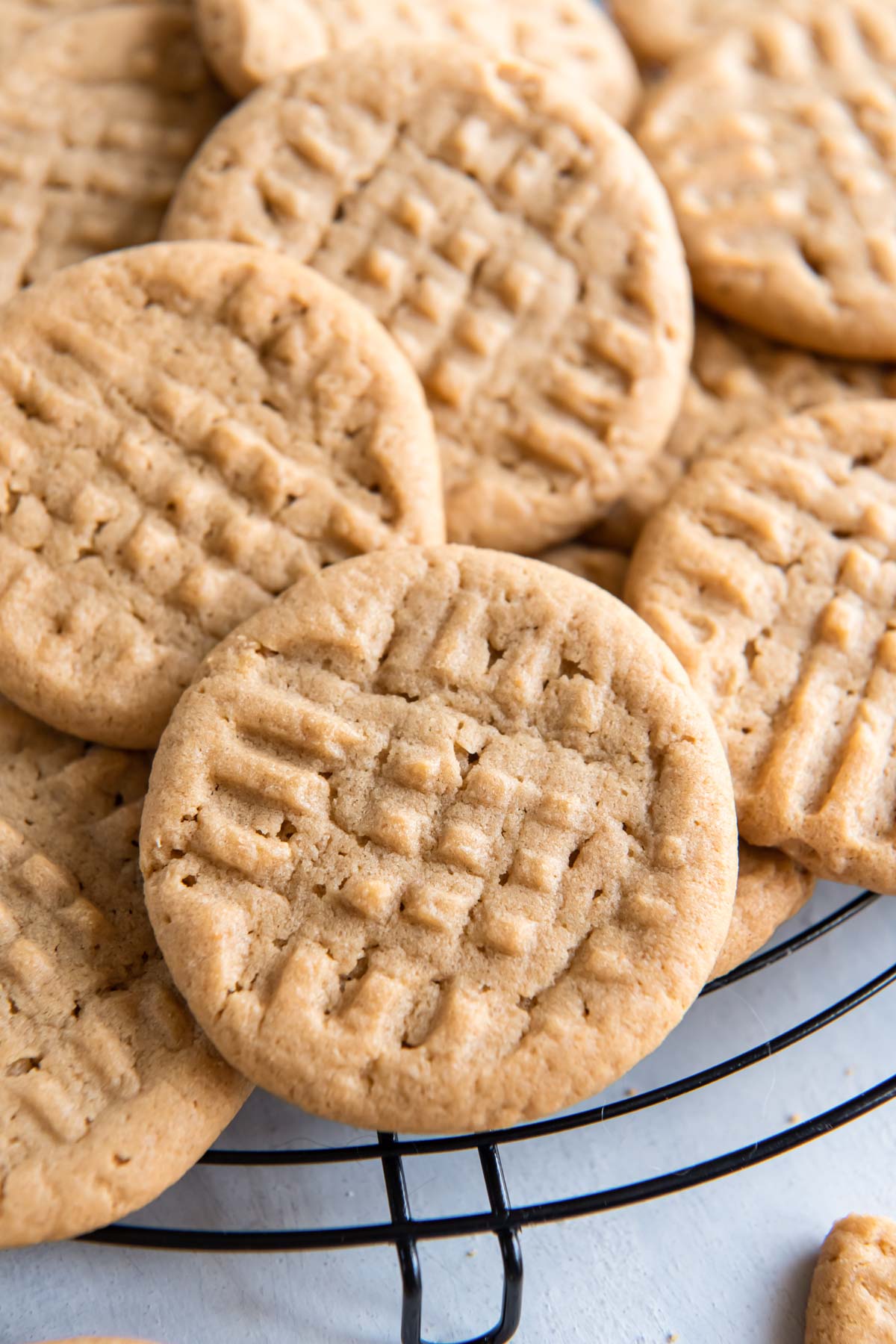 Close up of peanut butter cookies stacked together on a round cooling rack.