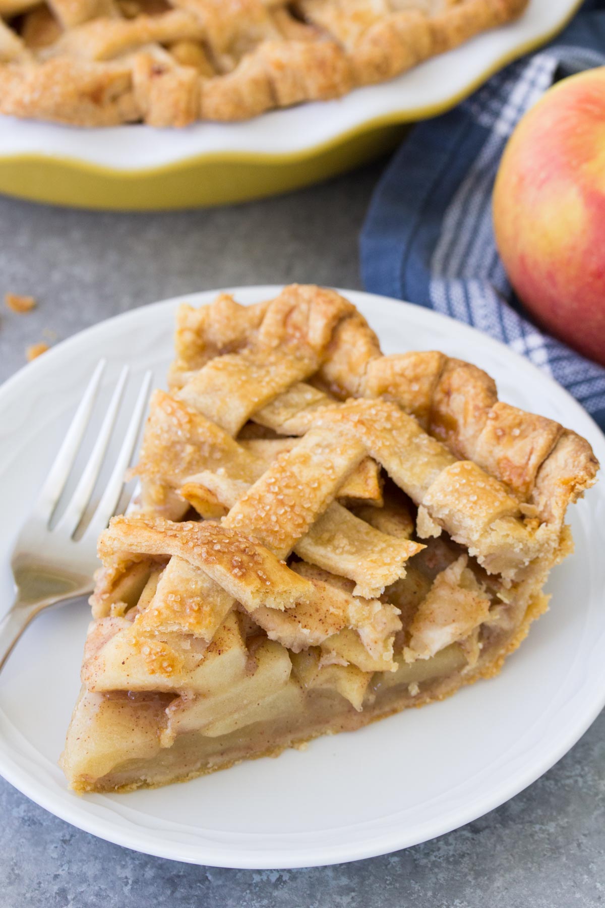 Slice of apple pie on a plate with a fork.