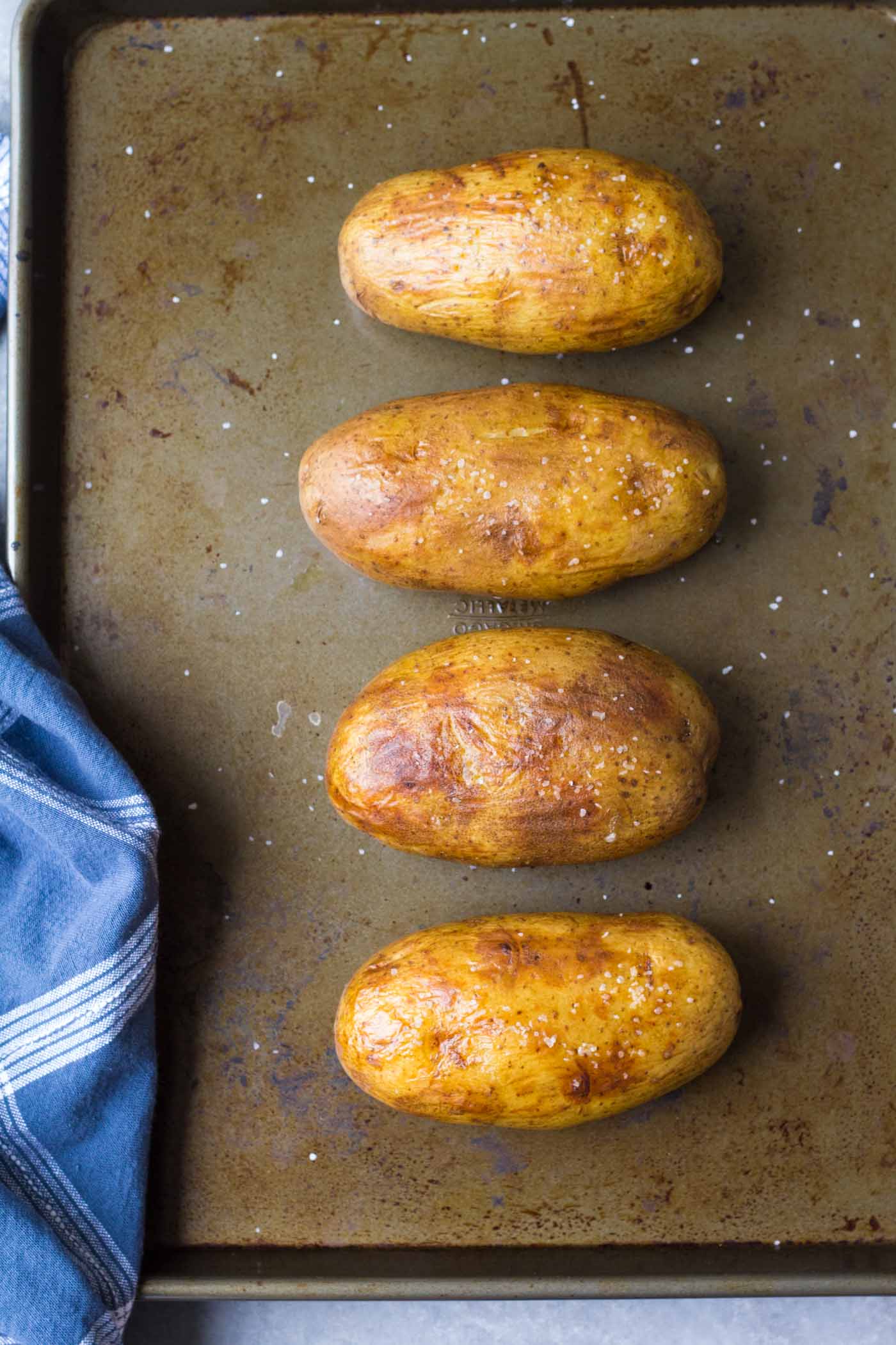 Four instant pot baked potatoes on a baking sheet after crisping in the oven.