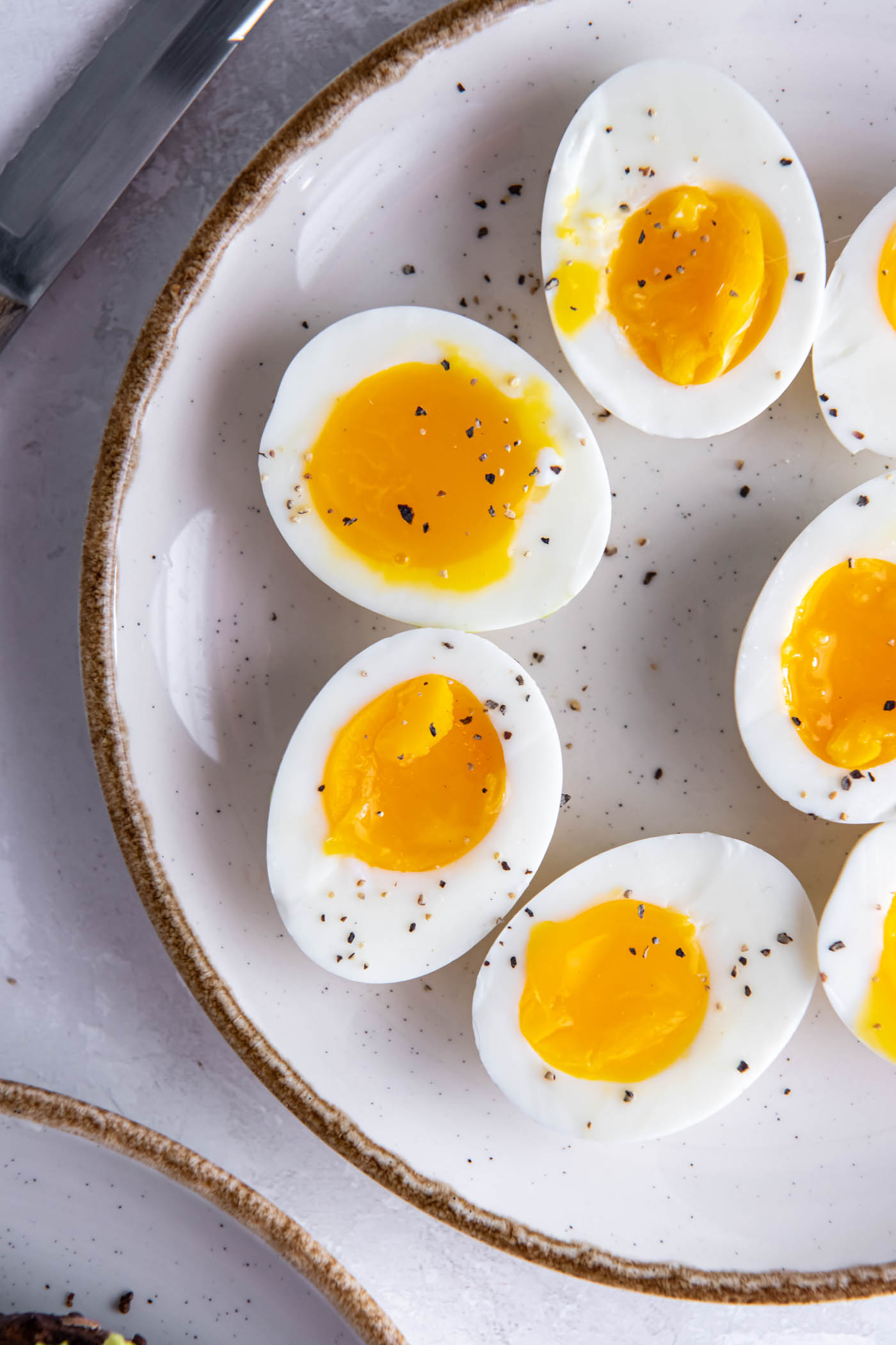 Halved soft boiled eggs on a plate with black pepper.