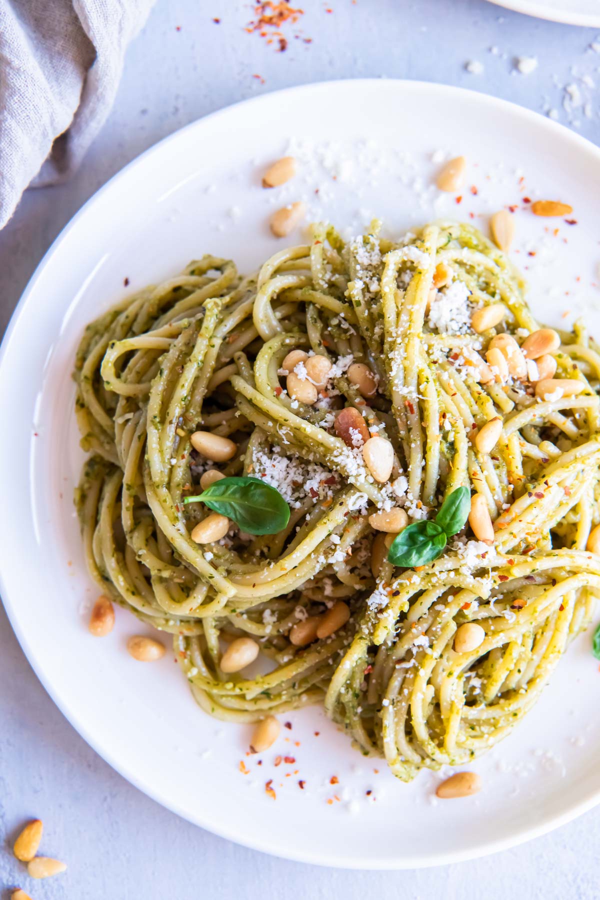 Pesto pasta with pine nuts, parmesan and basil served on a plate.