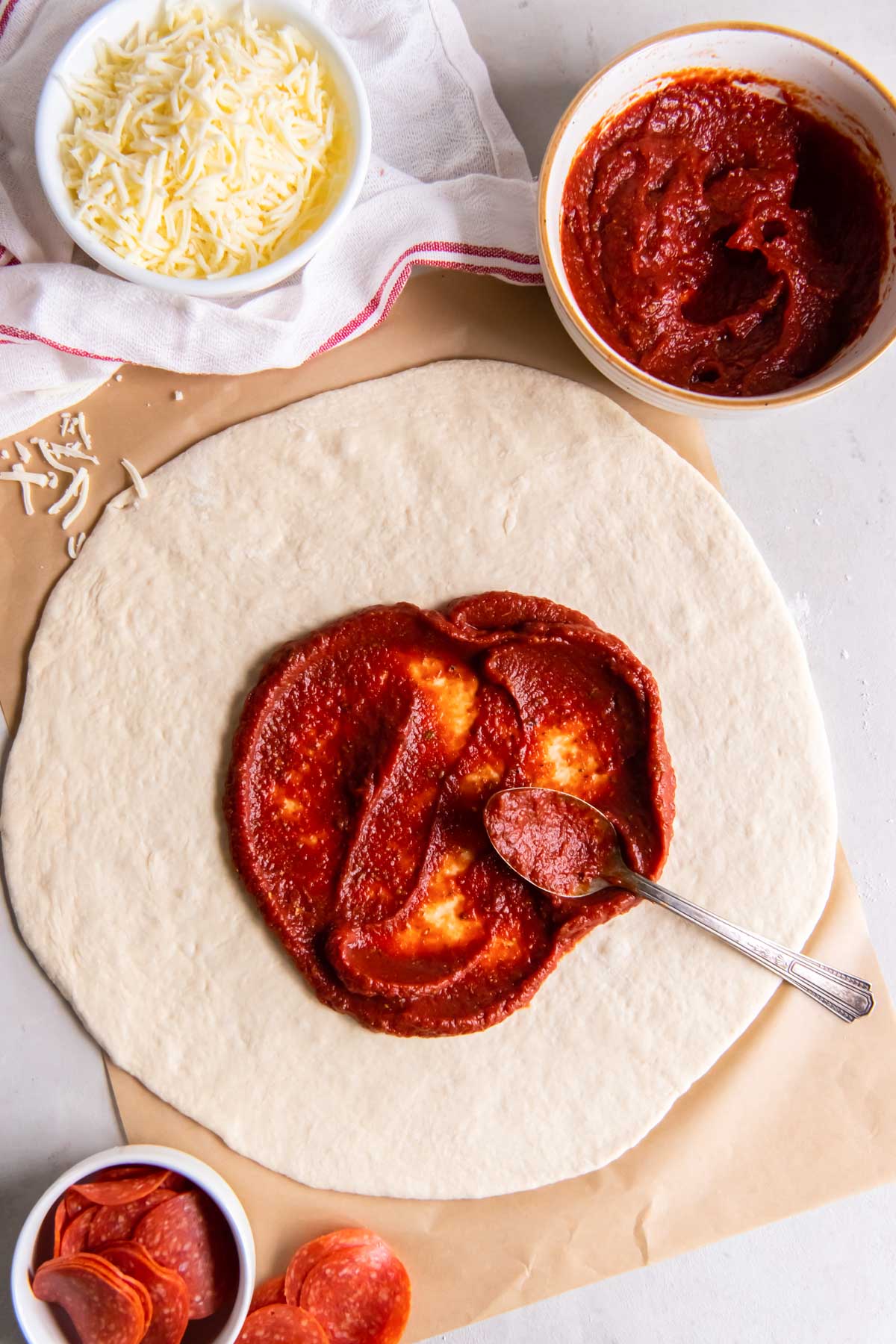 Spreading pizza sauce on pizza dough.