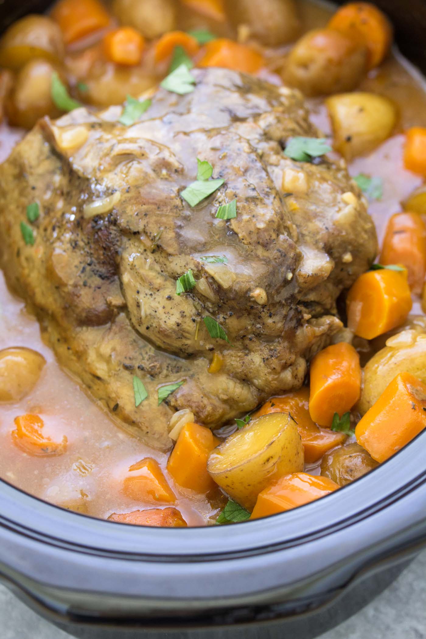 Pot roast in slow cooker with potatoes, carrots and gravy.
