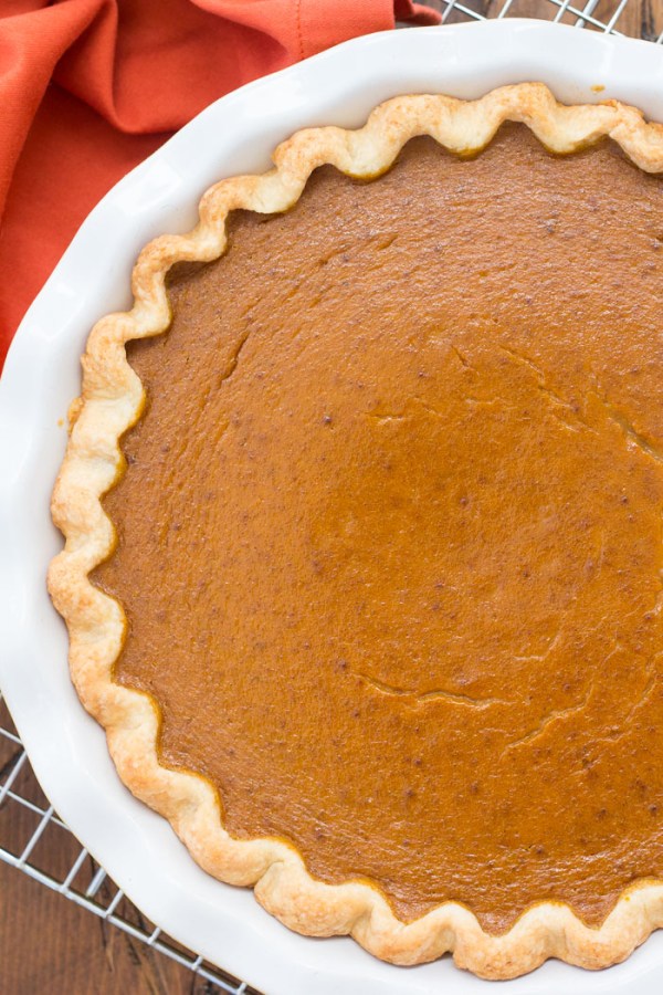 Top down view of a whole pumpkin pie on a cooling rack.