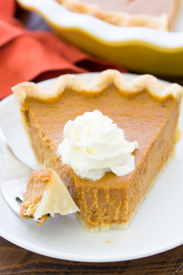 A slice of pumpkin pie with a bite on a fork.