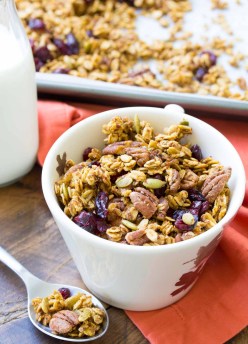 pumpkin spice granola in a cup with a spoonful and granola and milk in background
