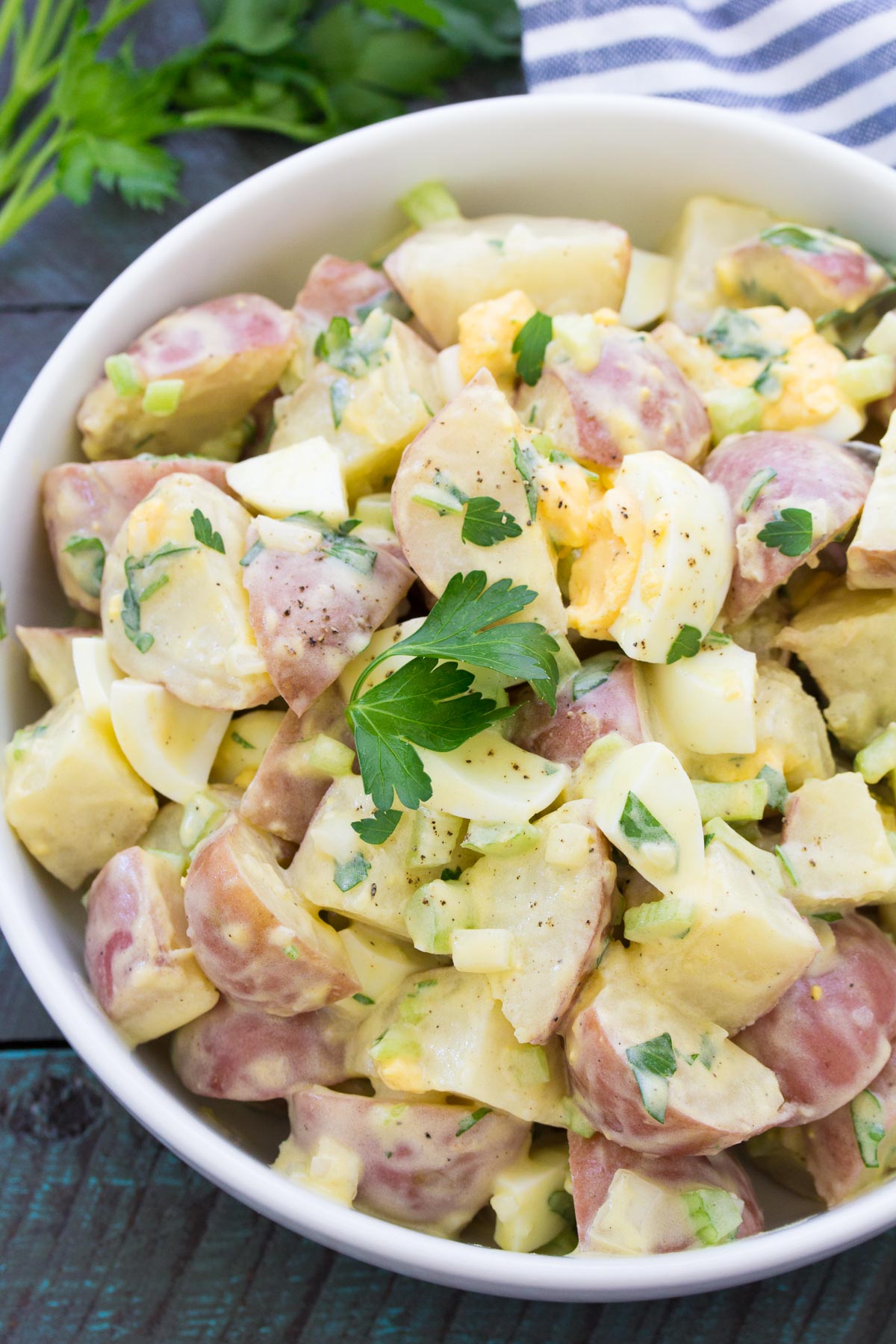 Red potato salad with hard boiled eggs in a white bowl.