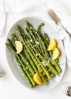 roasted asparagus with lemon and parmesan on a white oval plate