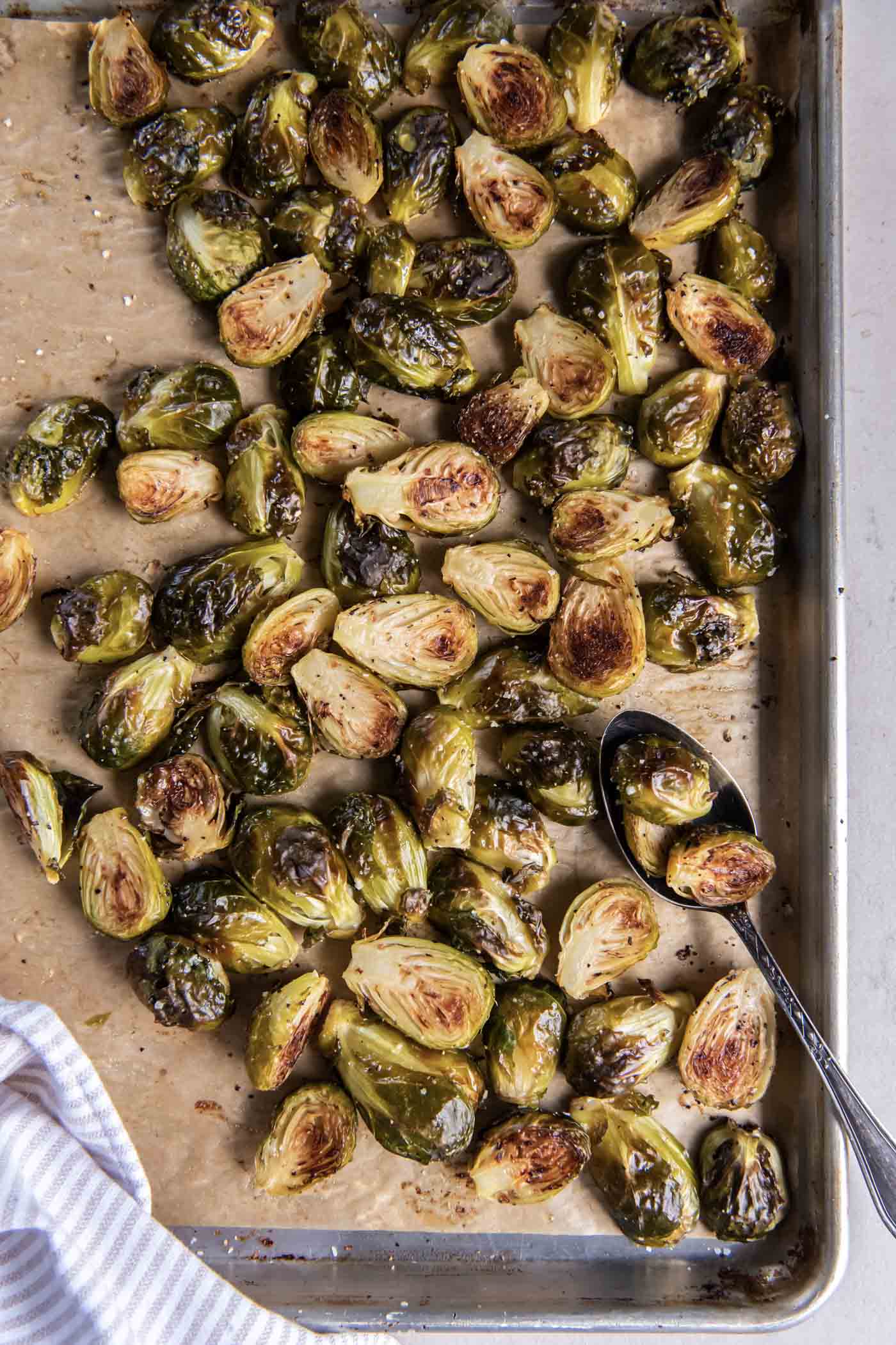 Roasted Brussels sprouts on a baking sheet with a spoon.