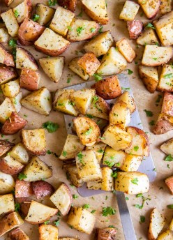Roasted red potatoes on a sheet pan with a metal spatula.