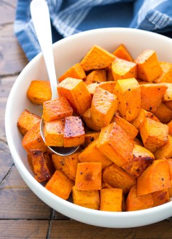 Honey roasted sweet potatoes in a serving bowl with spoon.