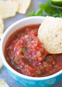 Homemade salsa served in small bowl with a tortilla chip.