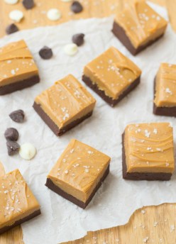 squares of caramel fudge on parchment with caramel and sea salt on top
