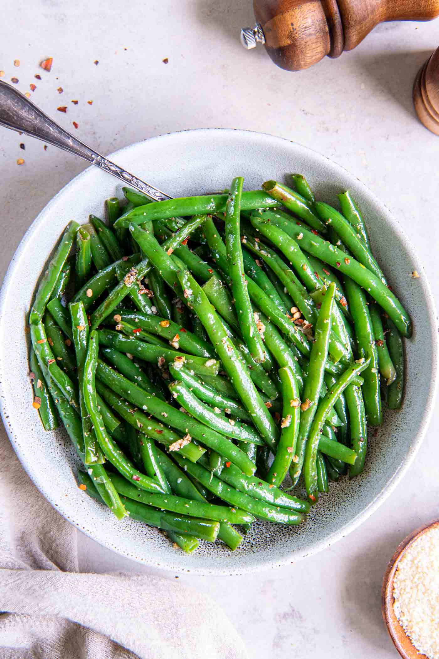 Sauteed green beans in a serving bowl with a spoon.