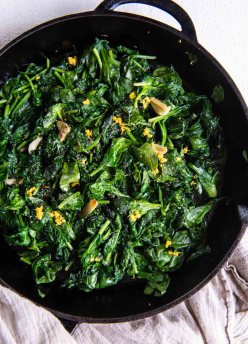 Sauteed spinach with garlic and lemon zest in a cast iron skillet.