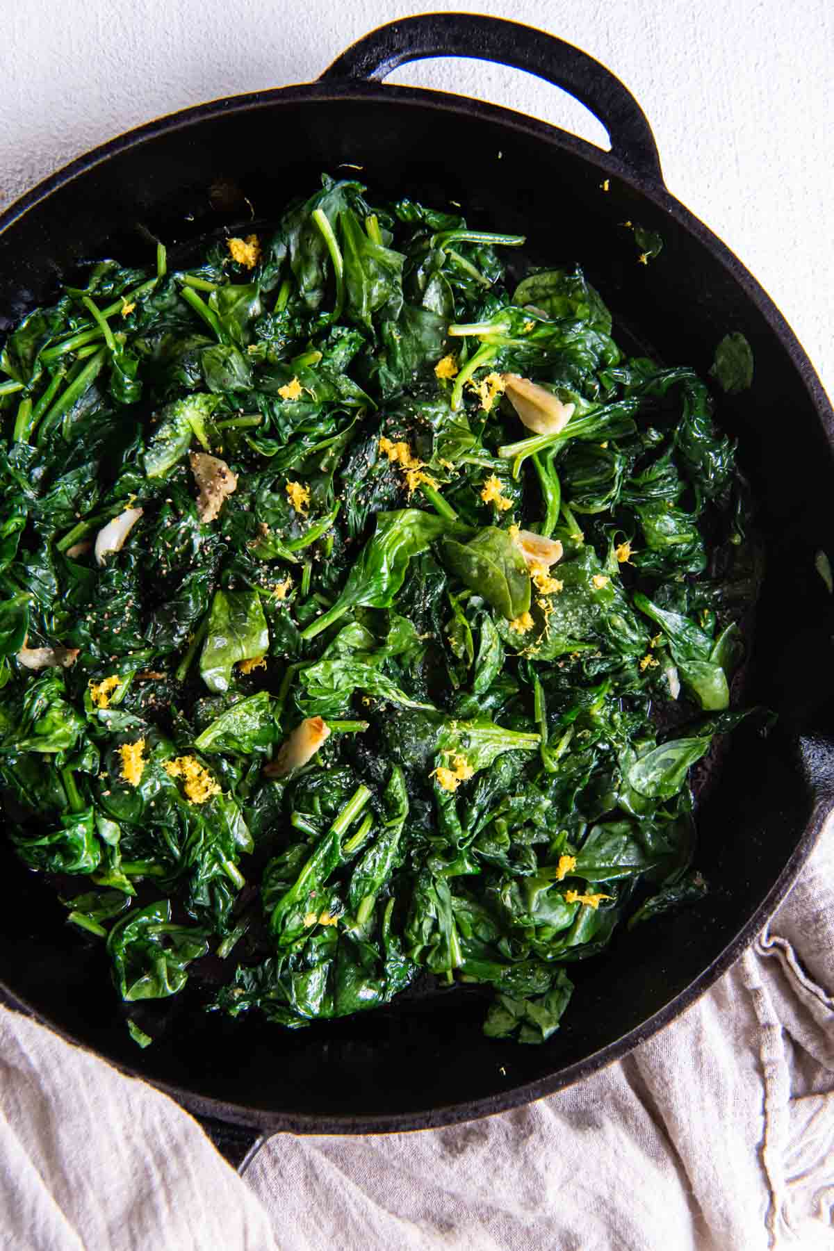 Sautéed spinach with garlic and lemon zest in a cast iron skillet.
