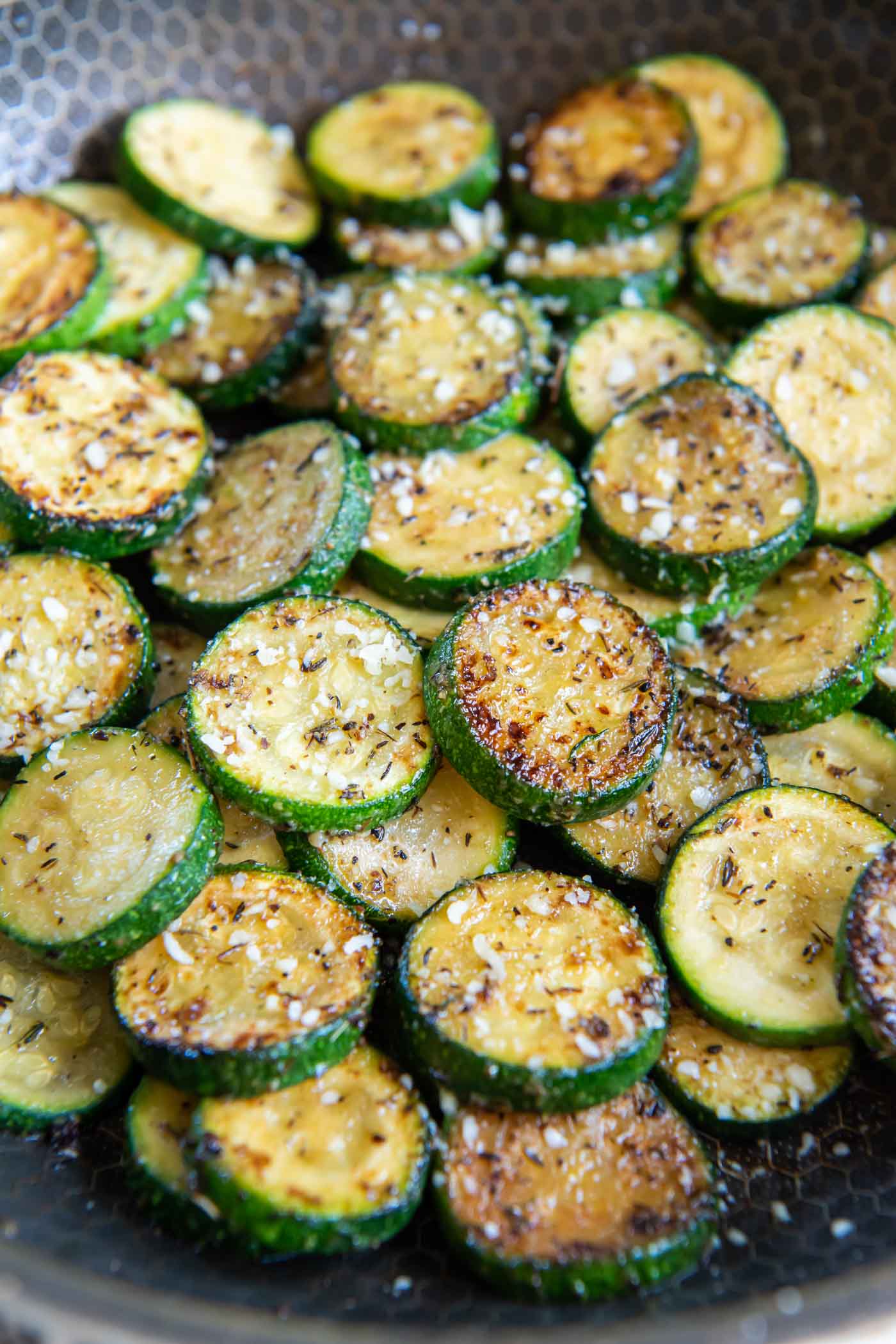 Sauteed zucchini with seasonings and parmesan in skillet.
