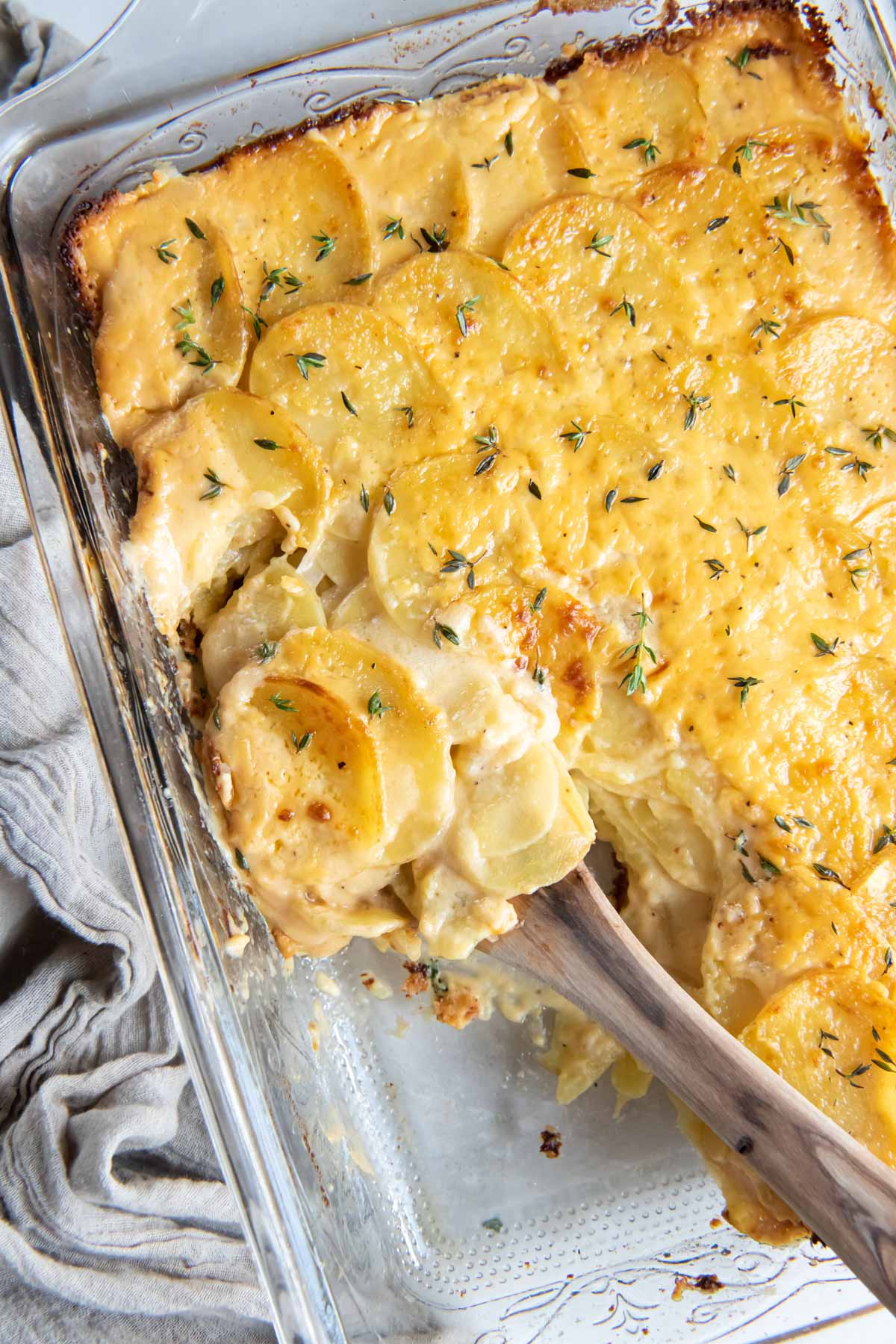 Scalloped potatoes in baking dish with serving spoon.