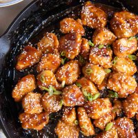 Sesame chicken in a cast iron skillet.