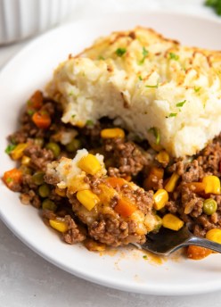 Close up of a serving of shepherd's pie on a plate with bite on a fork.