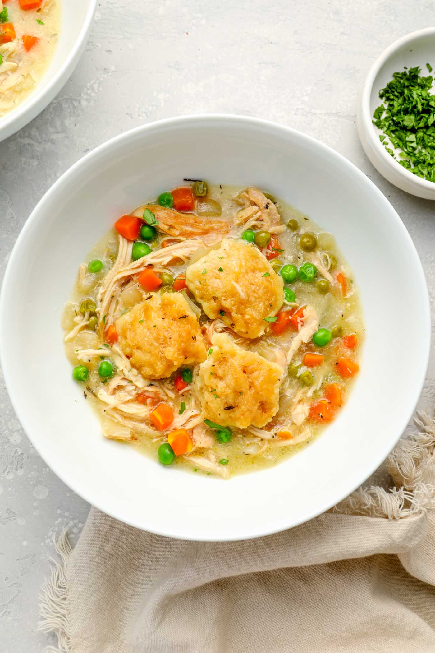 A serving of crock pot chicken and dumplings in a white bowl.