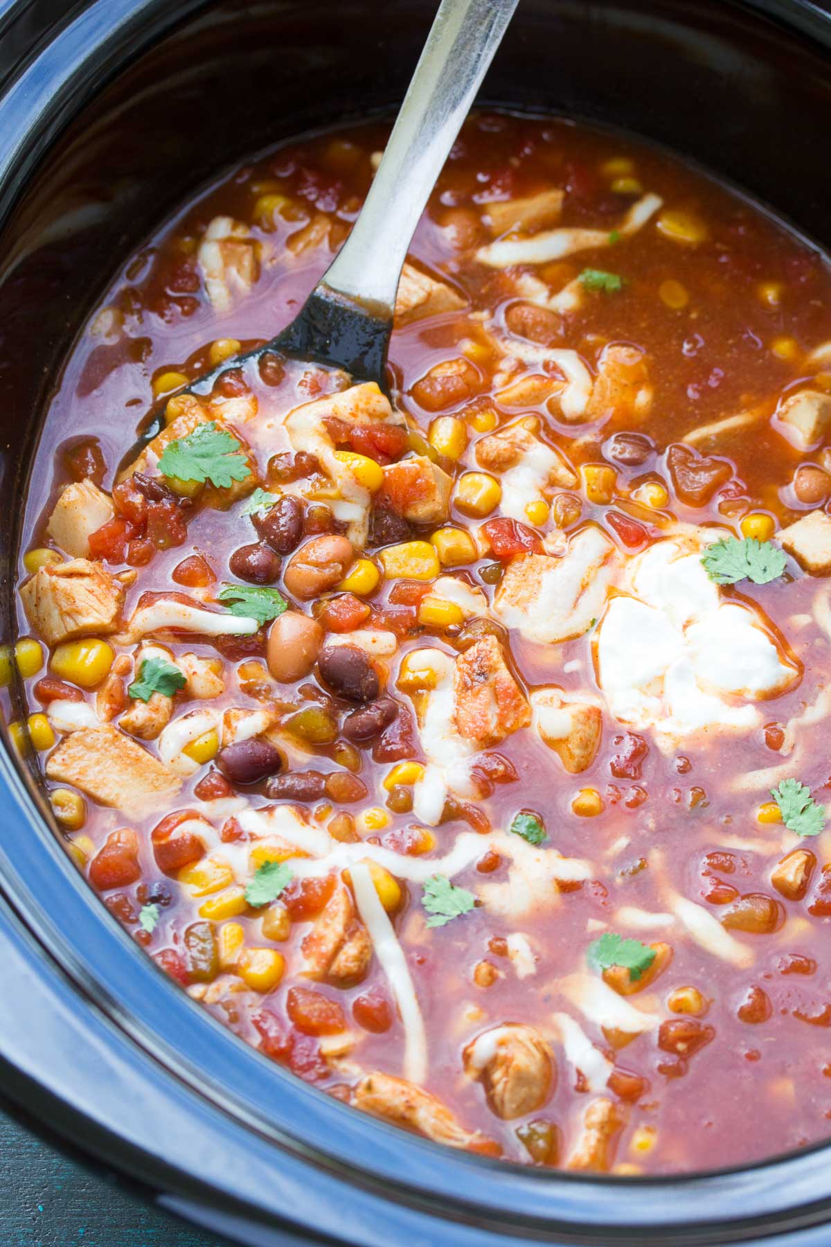 Chicken taco soup in a slow cooker with a serving spoon.