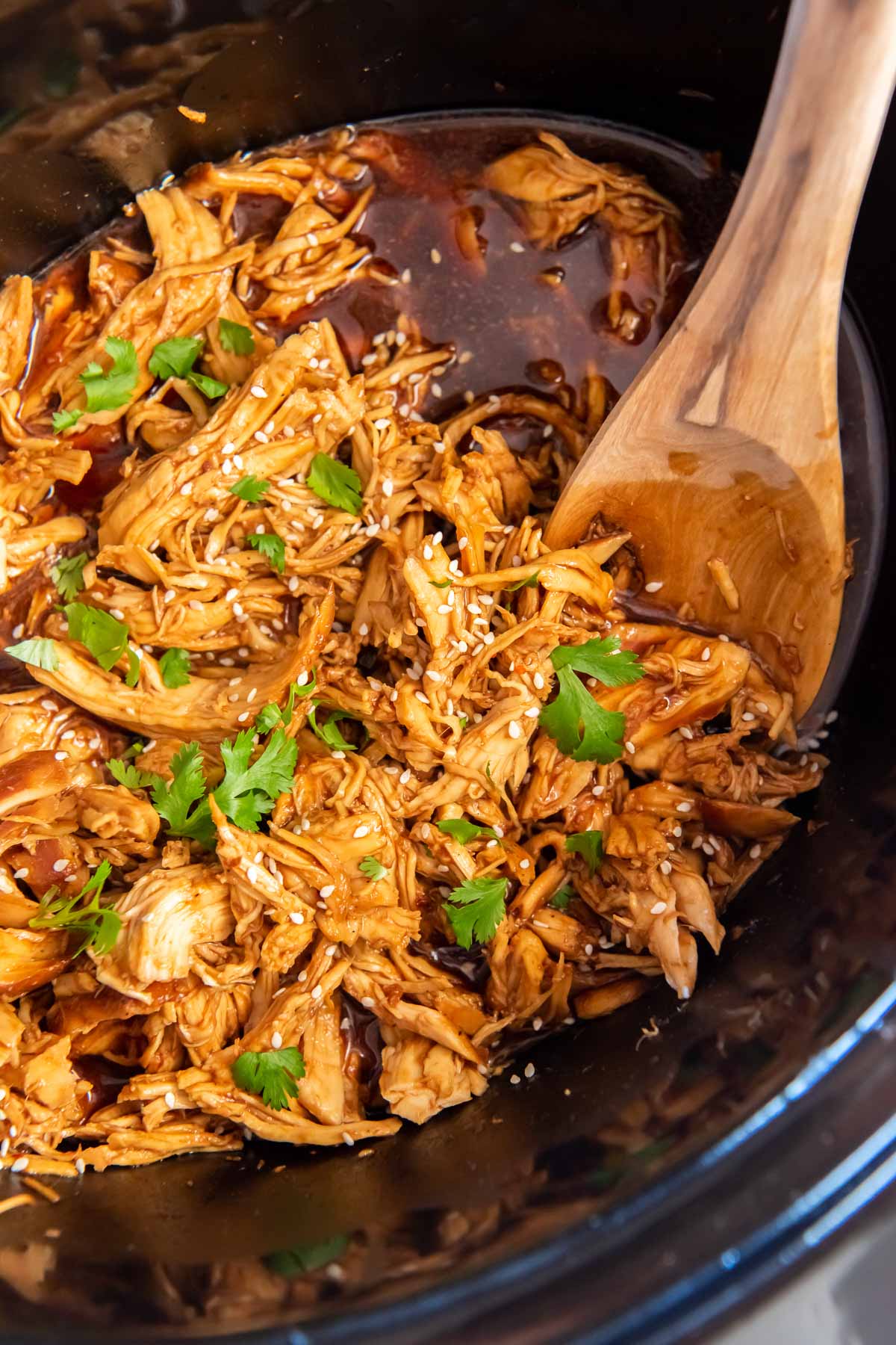 Shredded honey garlic chicken in a slow cooker.