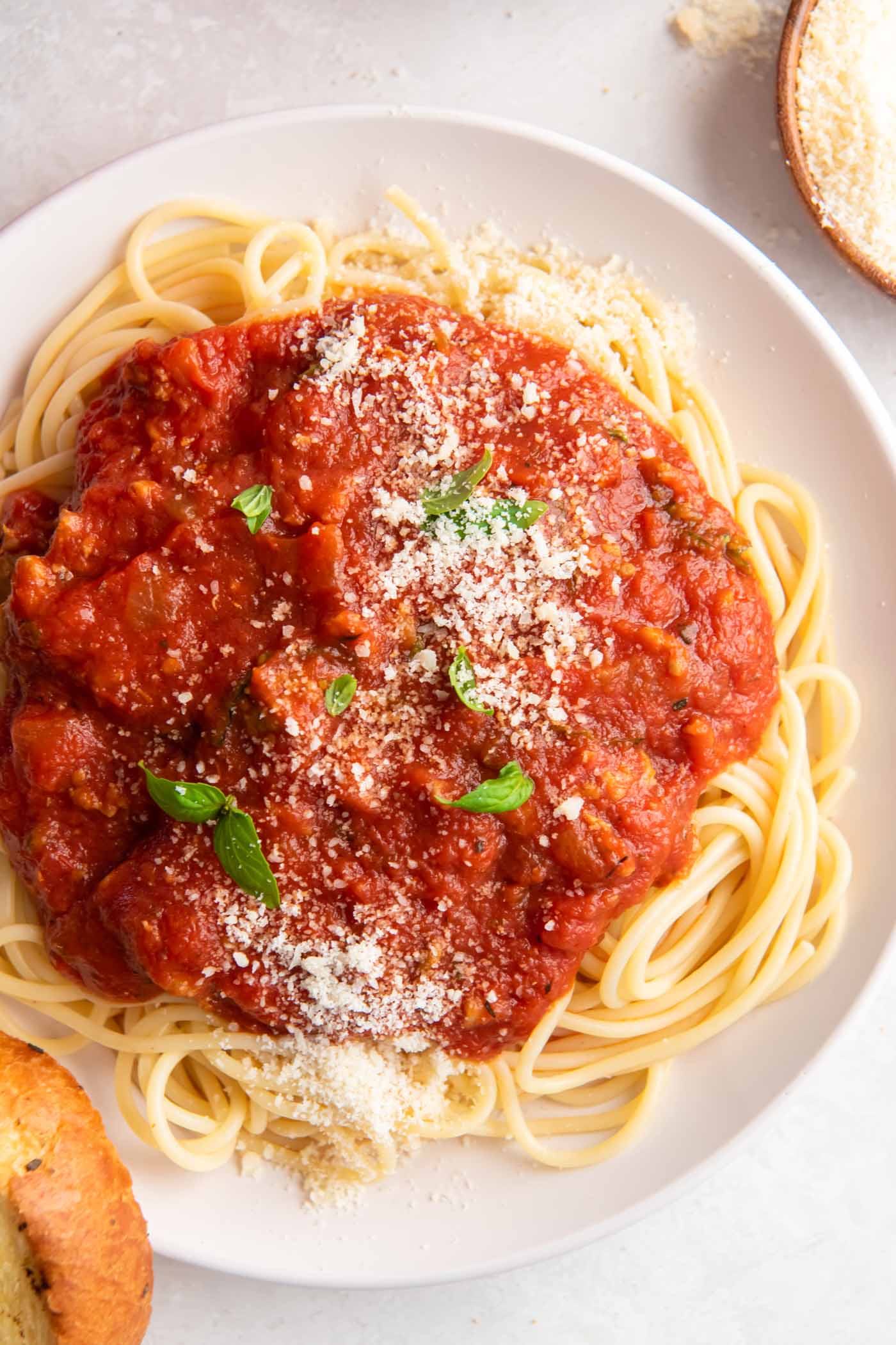 Homemade spaghetti sauce served over spaghetti with grated parmesan and fresh basil.