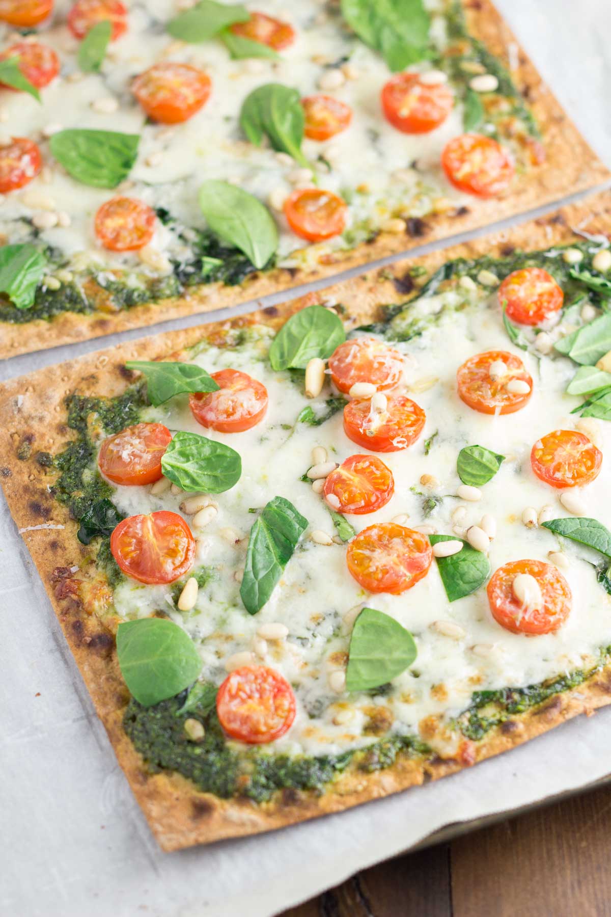 Spinach Pesto and Tomato Flatbread Pizzas - an easy dinner that you can have on your table in 30 minutes! These vegetarian pizzas are so good with a crispy whole wheat flatbread crust and crunchy pine nuts!