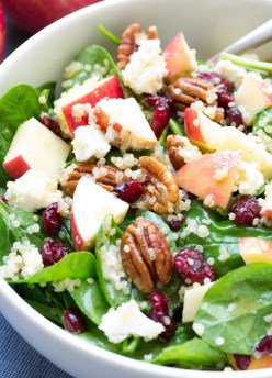 spinach salad with quinoa in white bowl