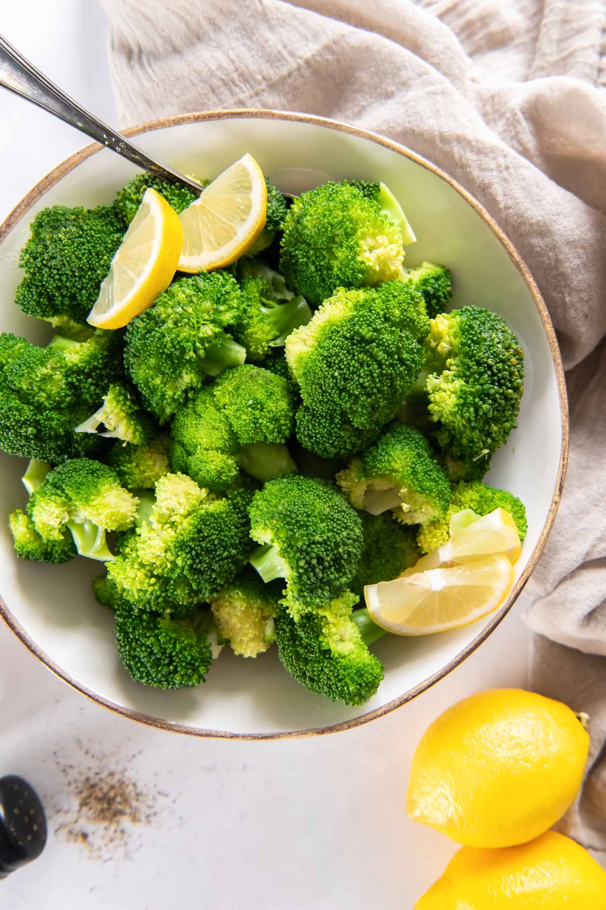 Steamed broccoli with lemon wedges in a serving bowl.