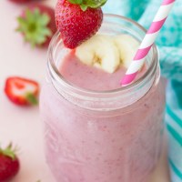 Strawberry banana smoothie garnished with a fresh strawberry and banana slices.