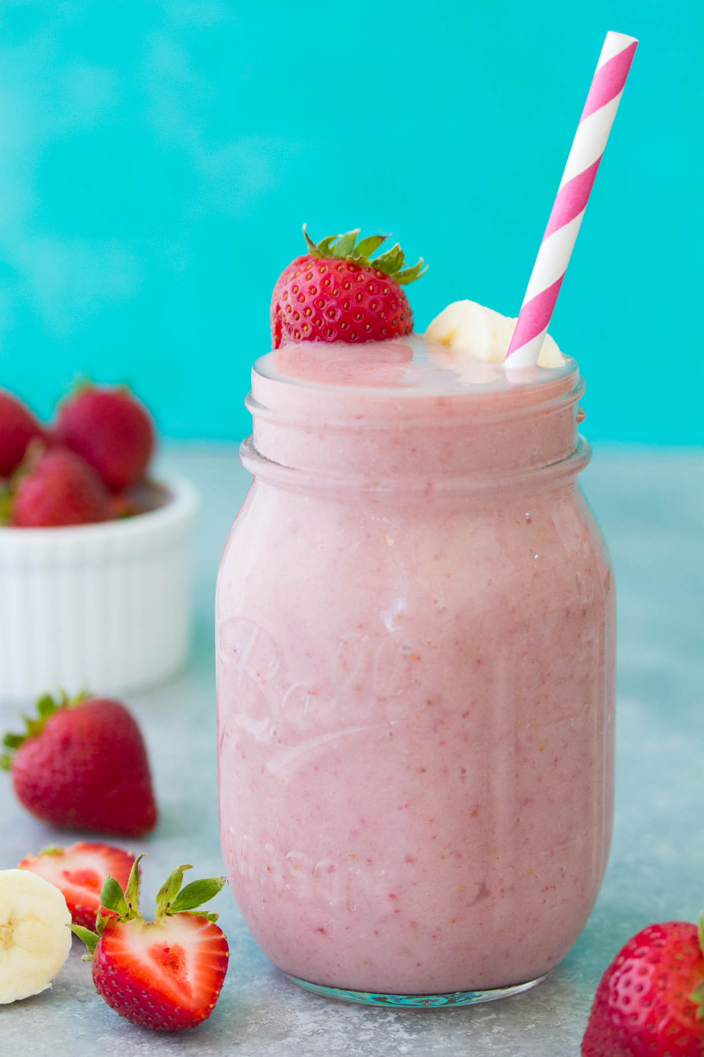 Side view of strawberry banana smoothie in a mason jar with a straw.
