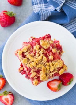 Overhead view of strawberry oatmeal bars stacked on a small white plate.