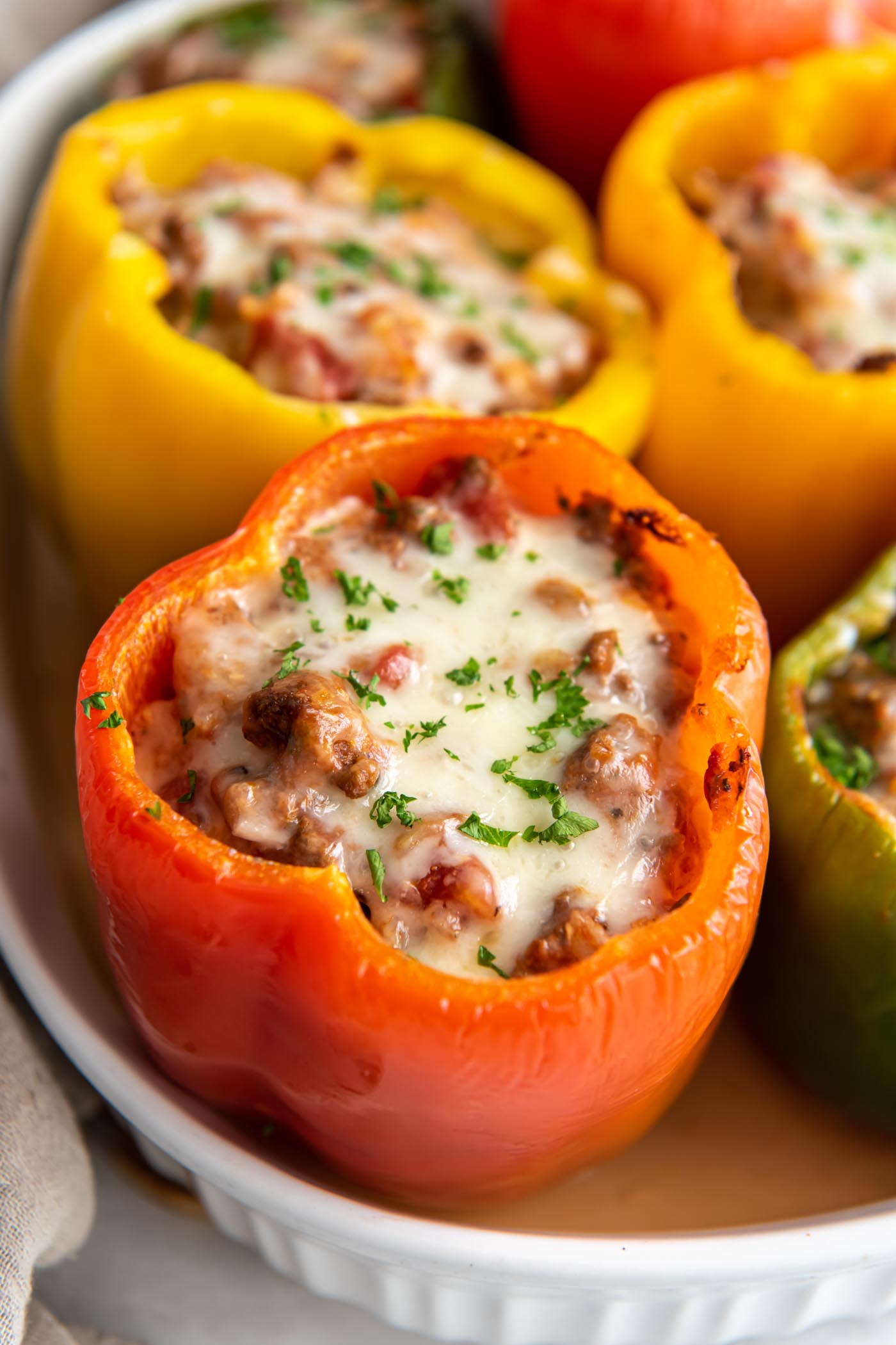 Close up of stuffed bell pepper topped with melted cheese and a sprinkle of fresh parsley.