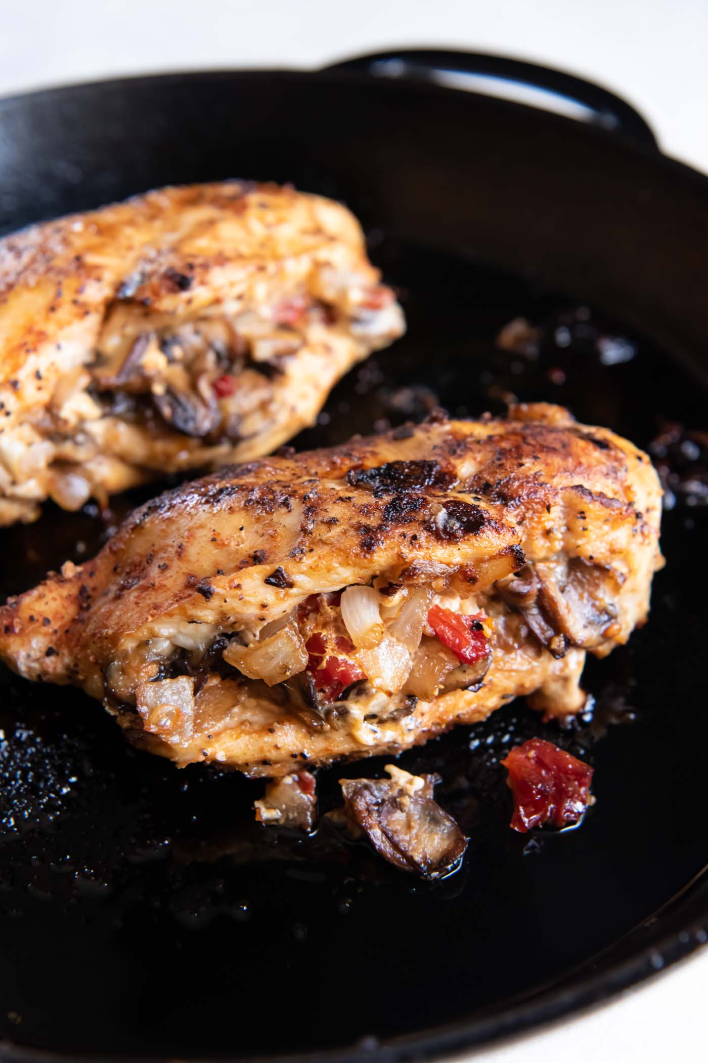Cooked stuffed chicken breasts in a cast iron skillet.