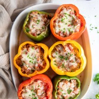 Six baked stuffed peppers in baking dish.
