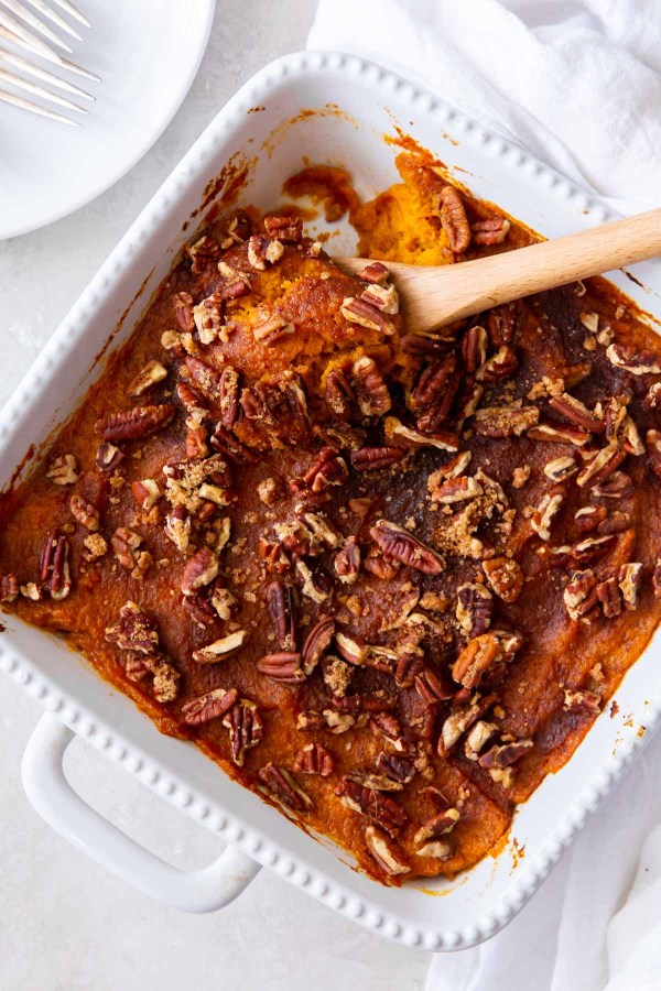 Sweet potato casserole in a white baking dish with a serving spoon.