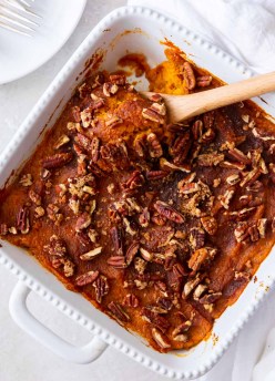 Sweet potato casserole in a white baking dish with a serving spoon.