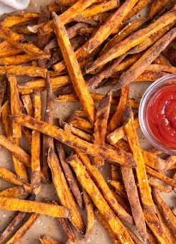 Baked sweet potato fries served with small dish of ketchup.