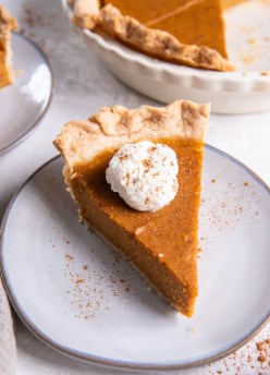 Slice of sweet potato pie topped with whipped cream.