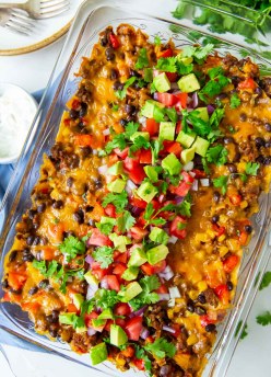 Taco casserole in baking dish with taco toppings on top.