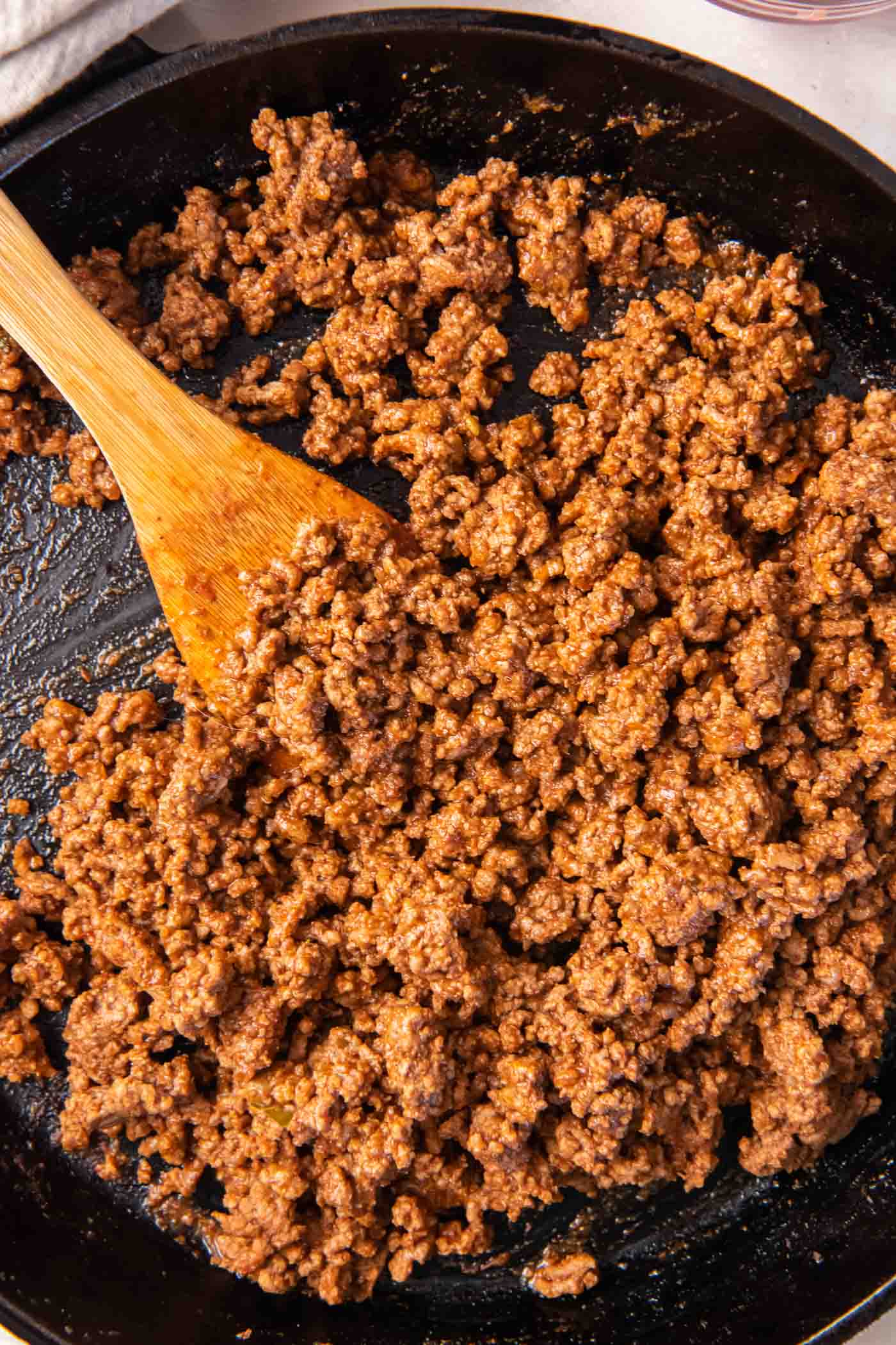 Taco meat in skillet with a wooden spoon.
