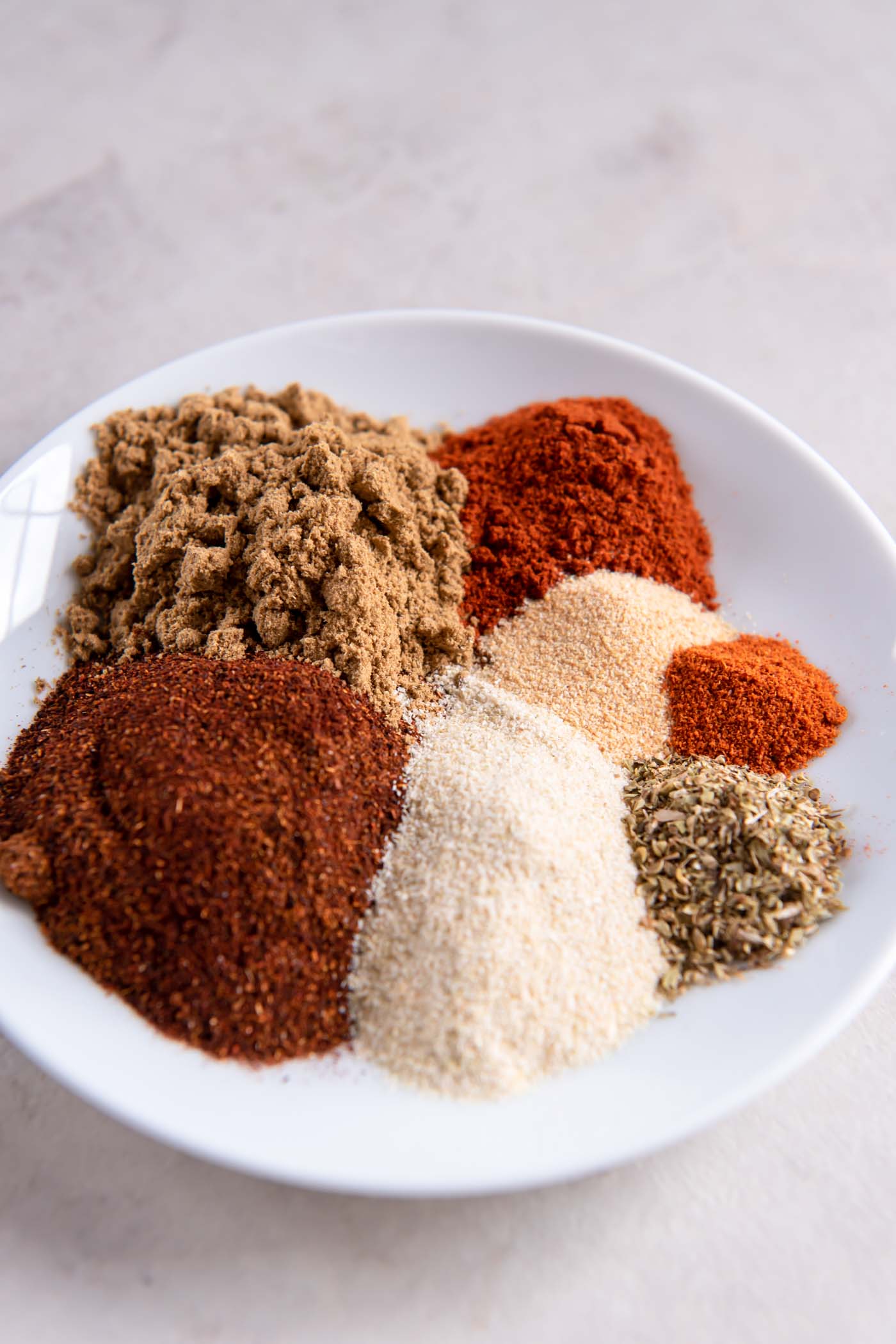 Spices for taco seasoning recipe added to a bowl in separate sections.