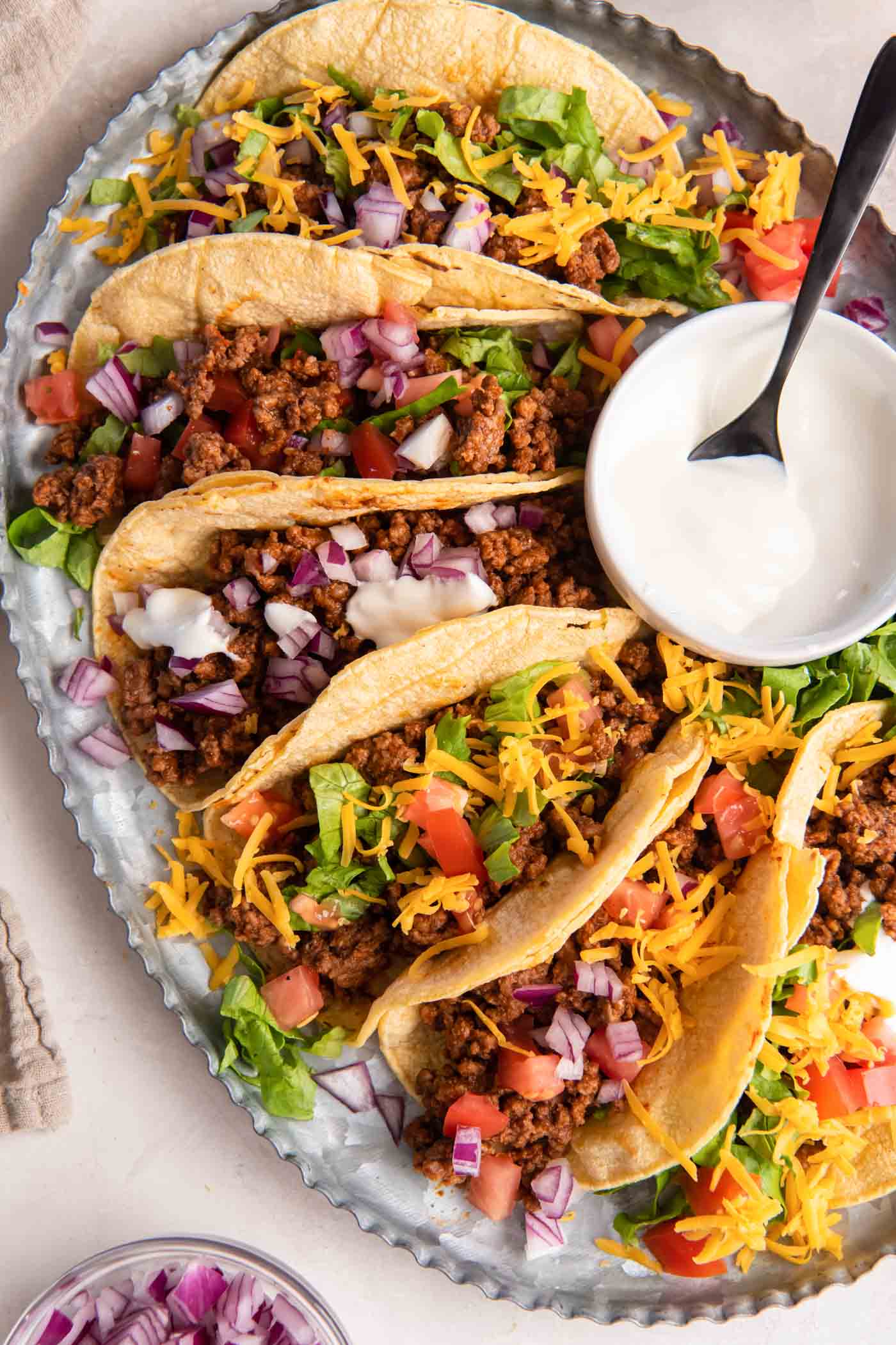 Ground beef taco meat served in corn tortillas with a variety of toppings.